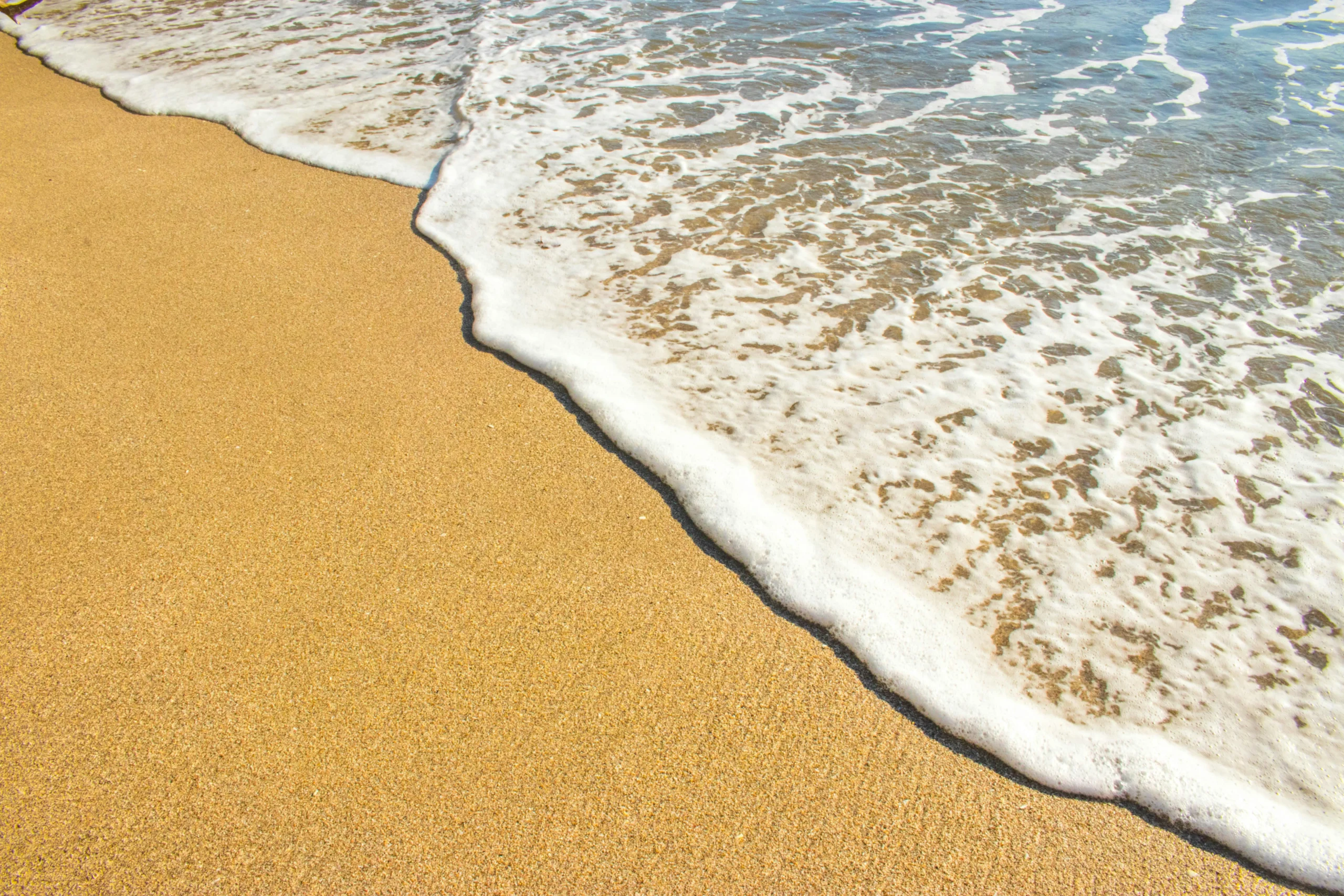 Peaceful beach scene showing sand meeting ocean waves in Puntarenas, Costa Rica.